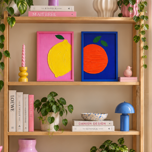 Die beiden Kunstwerke LES Fruites in einem modernen Holzregal mit skandinavischen Deko-Accessoires.