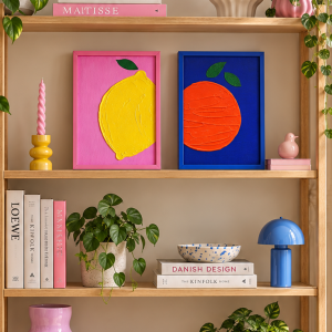 modernes Holzregal im Scandi Style mit bunter Deko. Passend zu den zwei Kunstwerken. Ein Kunstwerk ist Pink mit einer gelben Zitrone aus strukturpaste und ein Kunstwerk Kobaltblau mit einer Orange aus Strukturpaste.